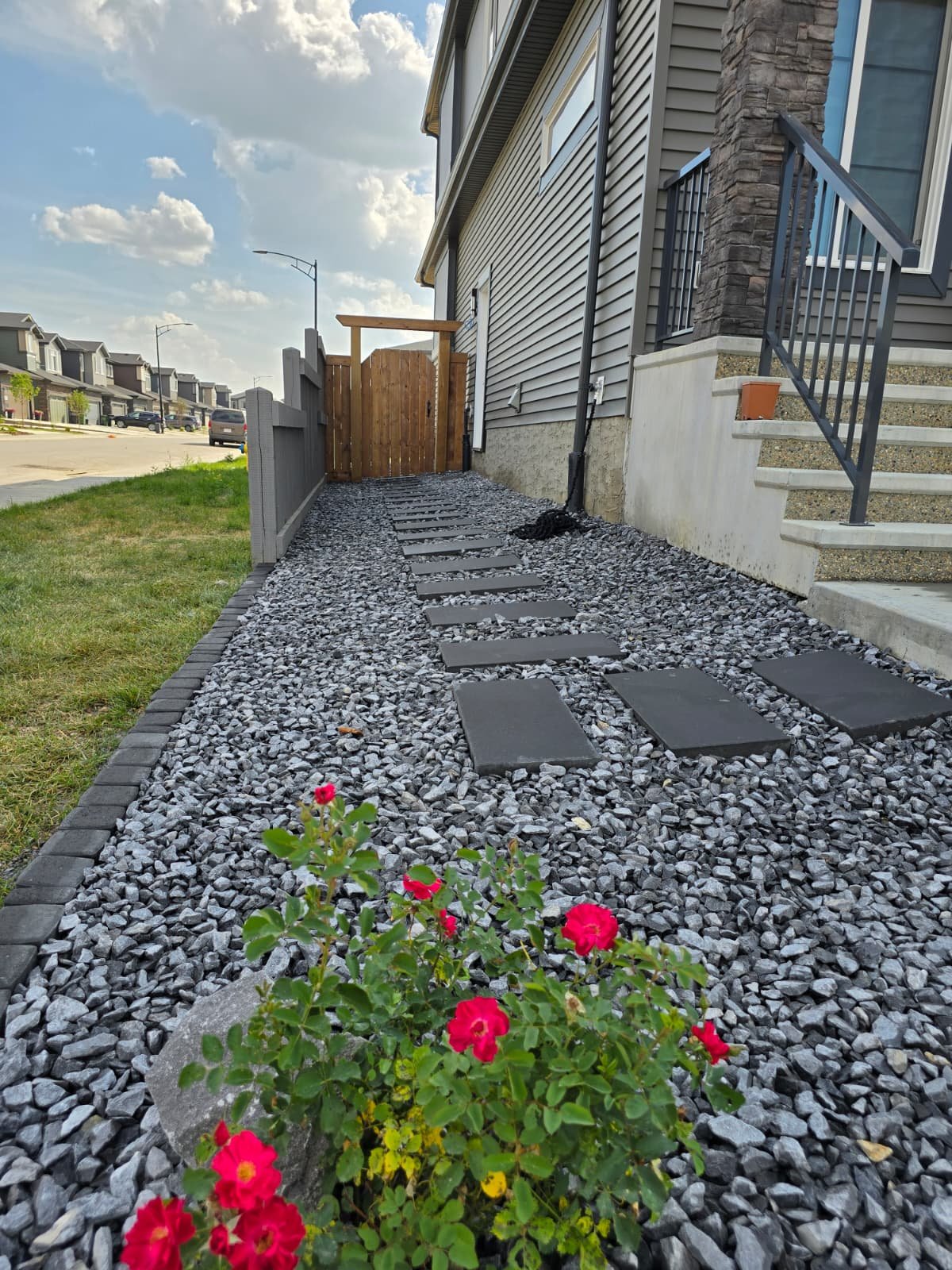 Dark slate steppers through grey gravel with pergola gate — Edmonton